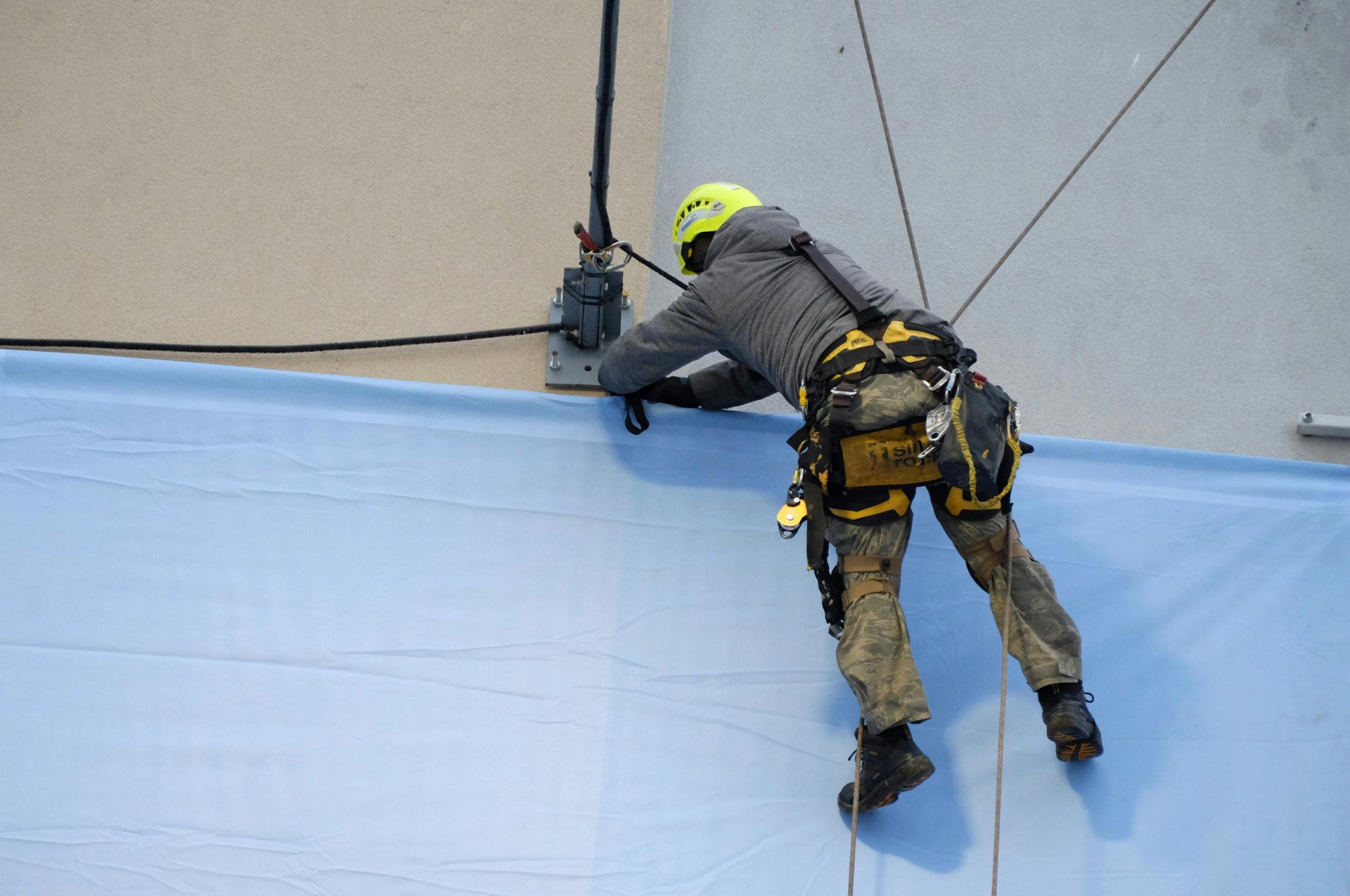 Rope access technician in safety gear fixes a large banner onto a building facade.