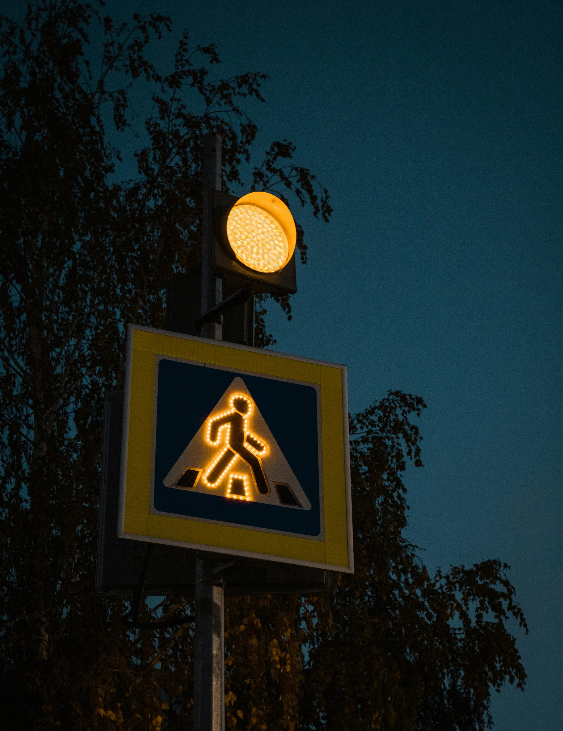 A glowing pedestrian crossing sign under a dusky sky, Tatarstan, Russia.